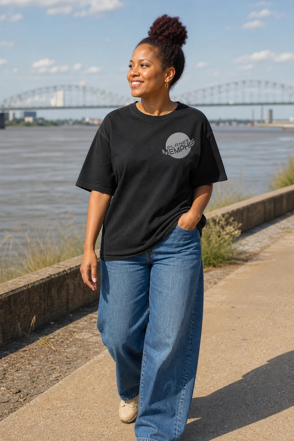 Black woman wearing a black Planet Memphis left-chest tee at the Memphis riverfront
